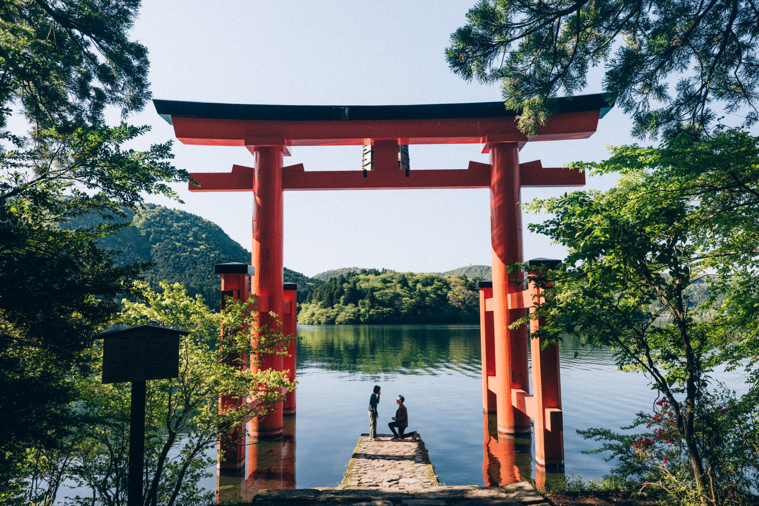 Surprise proposal photo shoot at Hakone Shrine’s Peace Torii gate with Lake Ashi and mountain views, capturing natural and candid moments.