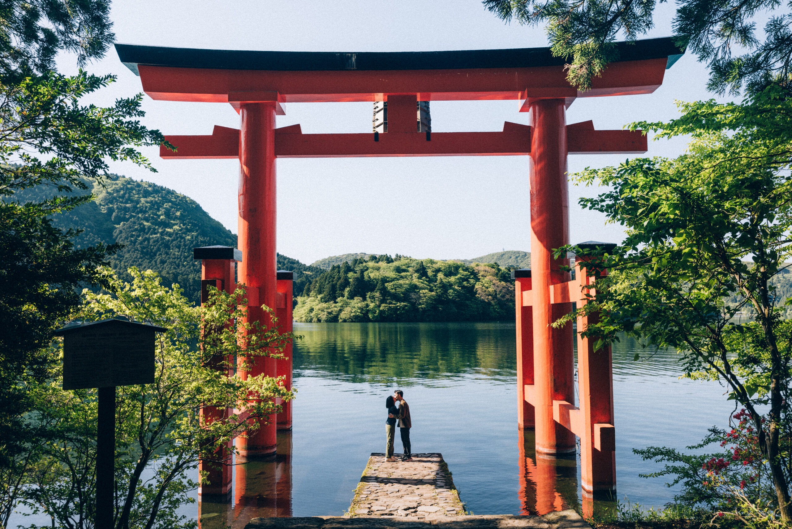 Surprise proposal photo shoot at Hakone Shrine’s Peace Torii gate with Lake Ashi and mountain views, capturing natural and candid moments.