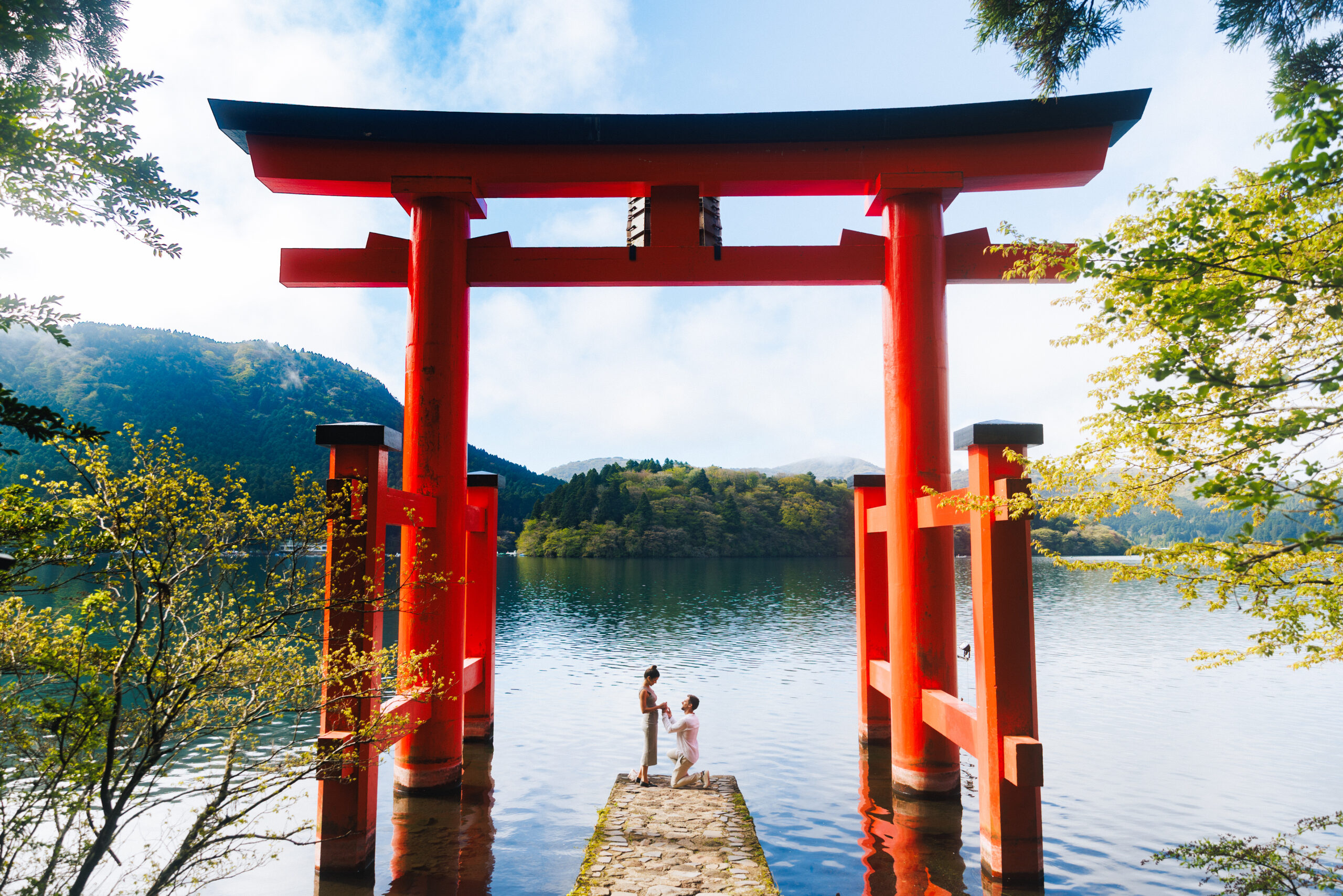 Surprise proposal photo shoot at Hakone Shrine’s Peace Torii gate with Lake Ashi and mountain views, capturing natural and candid moments.