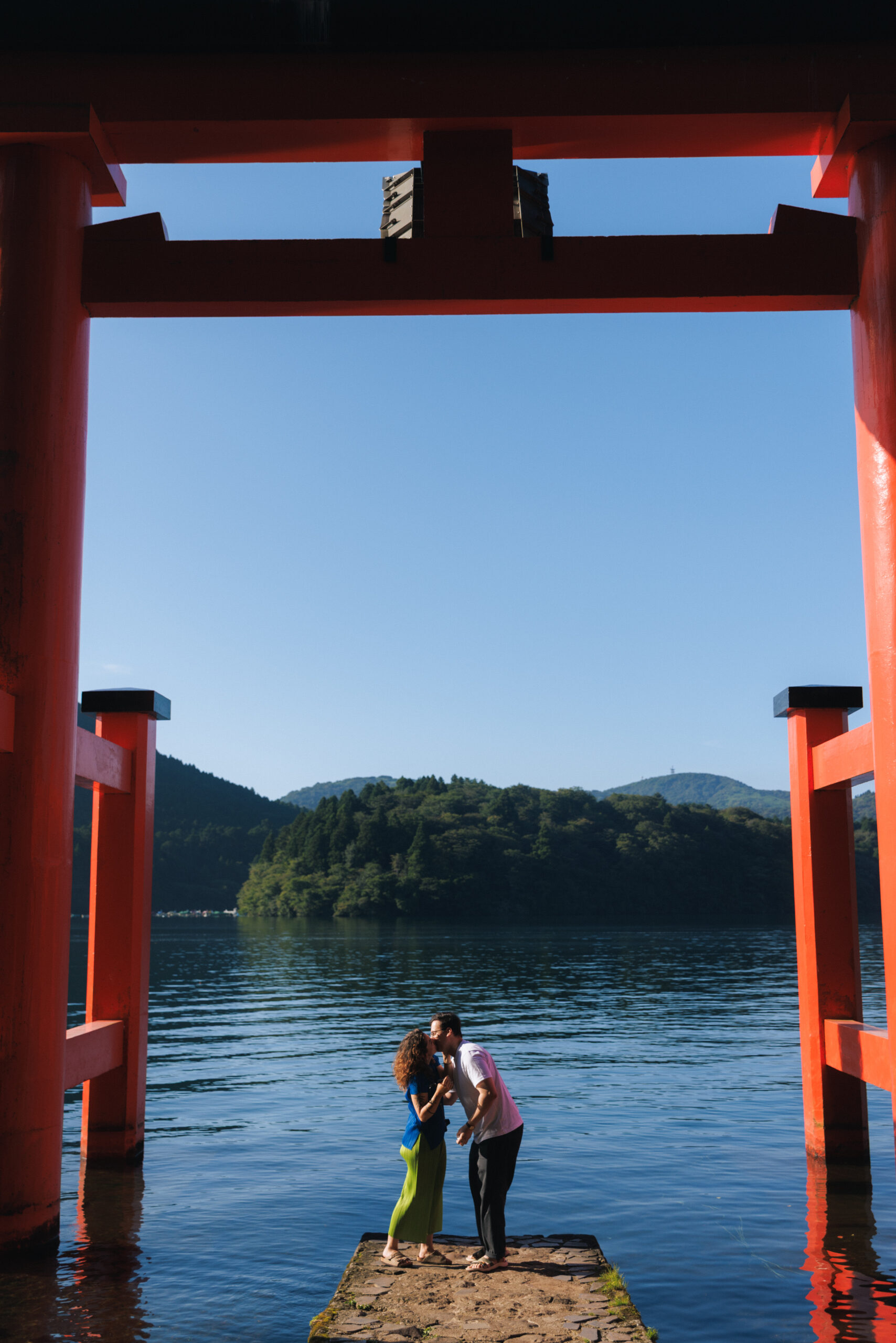 Surprise proposal photo shoot at Hakone Shrine’s Peace Torii gate with Lake Ashi and mountain views, capturing natural and candid moments.